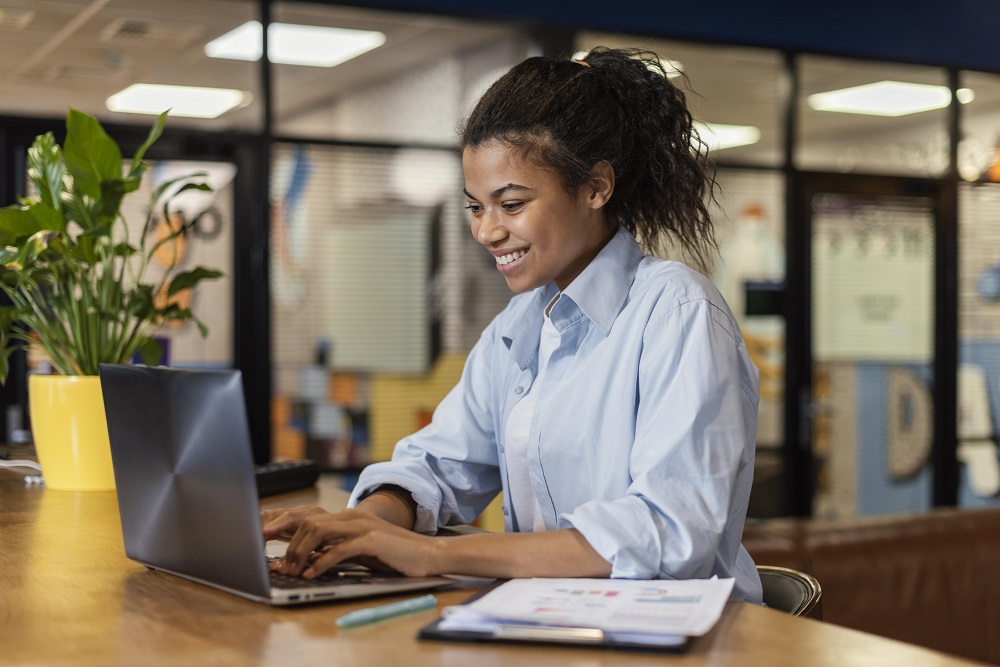 Mulher negra usando computador em ambiente de escritório, fazendo análise SWOT