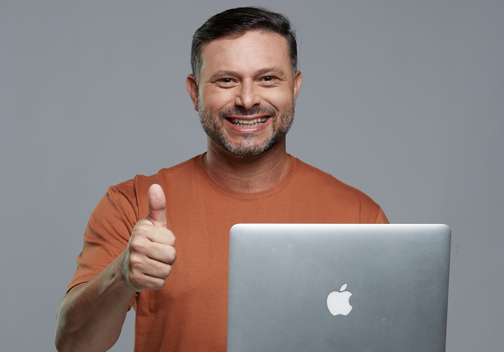 Homem usando computador e sorrindo para a foto